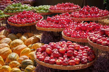 Many large ripe pumpkins of different varieties, green and red apples, and ripe pomegranates  lie in the open air.