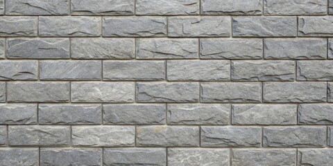 Fototapeta premium A close up of a grey brick wall with a rough, textured surface and a staggered pattern.