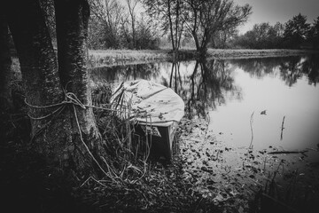 an old rowing boat lies on the shore of a lake in autumn