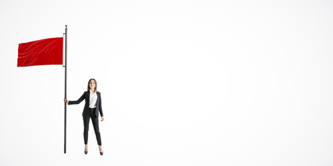 Businesswoman holding a large red flag while standing confidently on a white background. Concept of warning or alert in business.