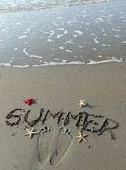 starfish and the large word summer carved on the sandy beach at the waters edge