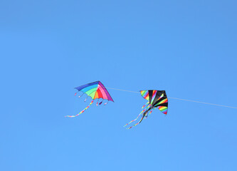two colorful kites with rainbow colors flying together in the sky