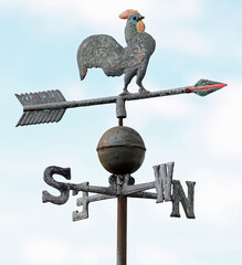 old weather vane with a rooster on top in a vintage style