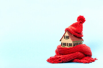 thermal insulation : miniature model house with red scarf and cap, blue background