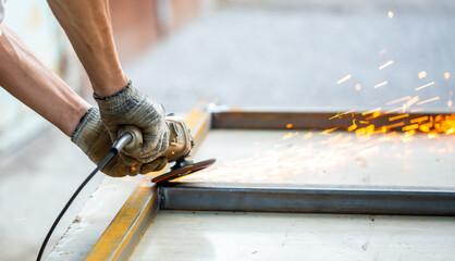 Grinding machine at work. Sparks fly from under the grinders, men's work. Dark background with copy space.