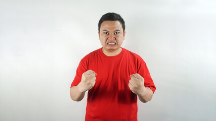 Naklejka premium A young Indonesian man wearing a red t-shirt with an angry face facing forward