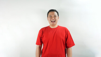 A young Indonesian man wearing a red t-shirt is laughing facing forward
