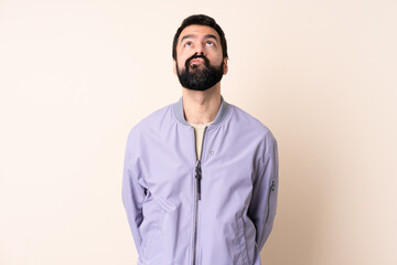 Caucasian man with beard wearing a jacket over isolated background and looking up