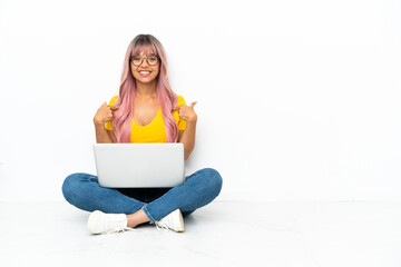 Young mixed race woman with a laptop with pink hair sitting on the floor isolated on white background with surprise facial expression