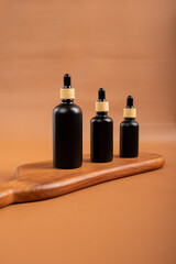 Black Glass Dropper Bottles with Cinnamon Sticks and Tealight Candles on Wooden Tray for Spa and Aromatherapy