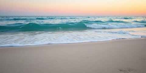 Fototapeta premium A soft blue ocean wave breaks on the shore of a tranquil fine sandy beach at sunset, creating a beautiful and serene scene, gentle movement, calm sea