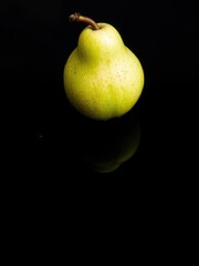 Fresh ripe pear with water droplets on a black reflective surface, nutrition, harvest, delicious
