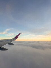 Obraz premium Sunset above clouds from a plane window, blue sky