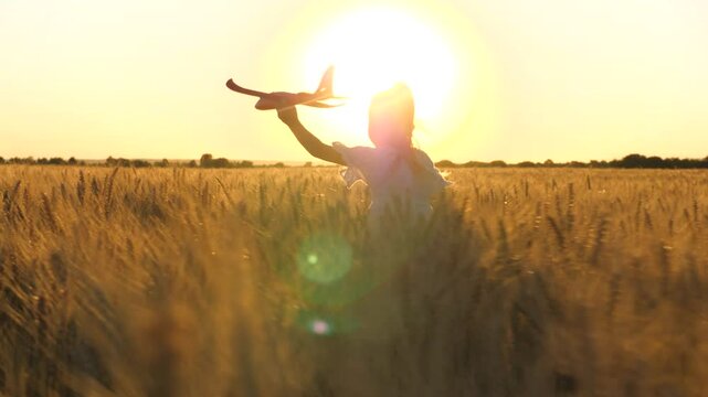 little child girl daughter runs through wheat field with toy plane her hand sunset, happy family dream fly, freedom concept, cheerful child runs through wheat field, kid plays with toy plane summer
