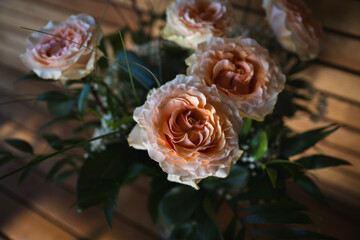 Bouquet of roses creme and apricot colored baroque roses in front of wooden background