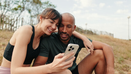 Close-up of athletic couple in love relaxing and using smartphone, front view