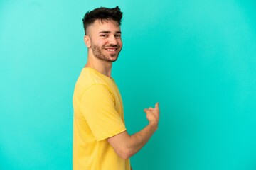 Fototapeta premium Young caucasian man isolated on blue background pointing back