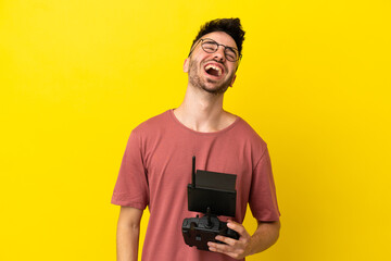 Man holding a drone remote control isolated on yellow background laughing