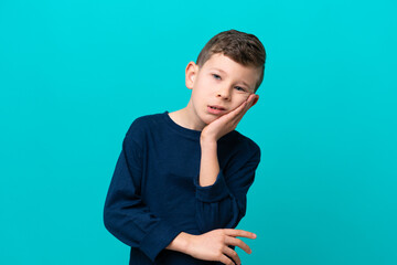 Little kid boy isolated on blue background with headache