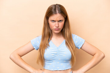 Young caucasian woman isolated on beige background angry