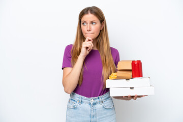 Young pretty blonde woman holding fast food isolated on white background having doubts and thinking