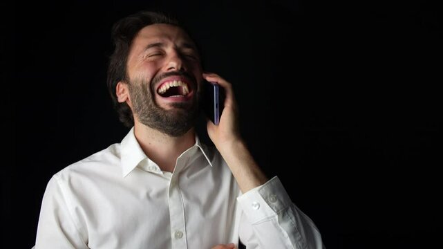 Man wearing white shirt is laughing while talking on the phone