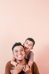 Fototapeta premium an asian boy hugs his father from behind with a happy expression
