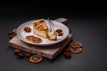 Delicious fresh cheesecake caramel peanut cake with cream and nuts on a ceramic plate on a dark...