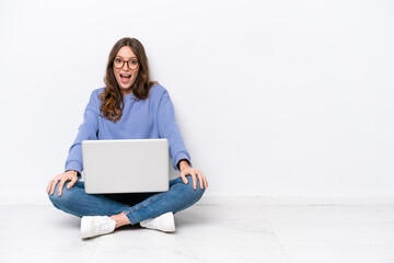 Naklejka premium Young caucasian woman with a laptop sitting on the floor isolated on white background with surprise facial expression