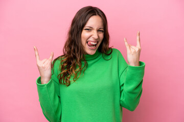 Young caucasian woman isolated on pink background making horn gesture