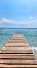 Obraz premium A wooden dock extends into the clear blue water of the Aegean Sea on a sunny day