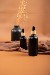 Matte Black Dropper Bottles with Minimalist Dried Floral Arrangement on Warm Brown Background