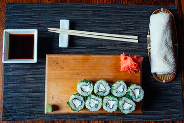 A tray of sushi with chopsticks and a dipping sauce