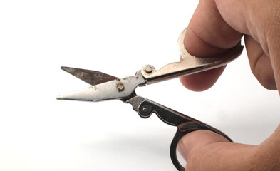 A hand holding the scissors in an open position, angled to show both blades and handles on a white...