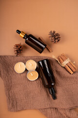 Amber Dropper Bottles with Candles and Cinnamon on Brown Fabric for Aromatherapy and Skincare