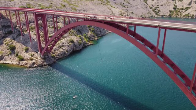 Bungee jumping activity from a bridge above the sea. Aerial view person attached to a rope on the bridge. Maslenica bridge, Croatia, travel destinations.