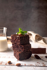 Chocolate brownies with melted chocolate topping, almond and leaves mint with glass of milk on...