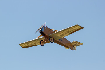 a historic wooden plane flies in a clear cloudless sky