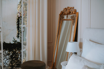 Elegant bedroom with a vintage mirror and balcony view during the day