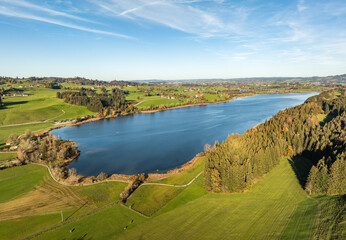 Naklejka premium aerial landscape photo of with Lake Niedersobthofener See between pastures and colorful autumn forests in the upper Allgaeu near Kempten
