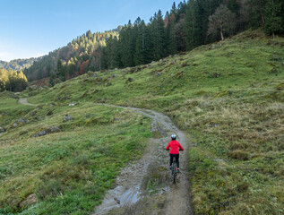 woman riding her electric mountain bike in the Bregenz Forest mountains near Hittisau, Vorarlberg...