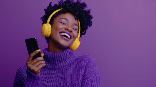 A woman is smiling and holding a cell phone while wearing headphones