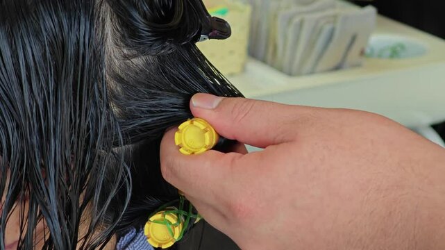 A hairdresser put hair in digital perm rod for the perm machine.