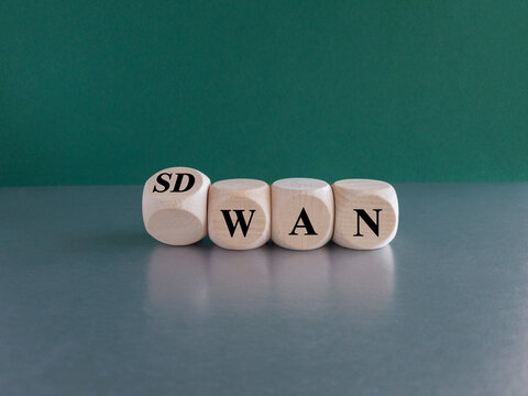 Dice form the expression SD WAN. Symbol for Software defined Wide Area Networking. Beautiful green background, grey table.