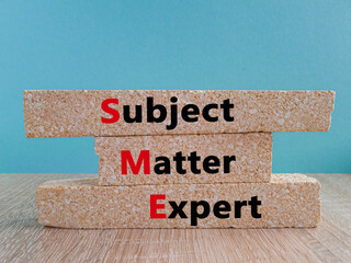 Concept words SME, subject matter expert on brick blocks on a beautiful blue background, wooden table. Business, SME, subject matter expert concept.