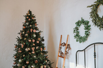Decorated Christmas tree with wreaths and vintage ladder in cozy room