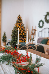 Festive holiday table setting with candles, greenery, and Christmas tree decor