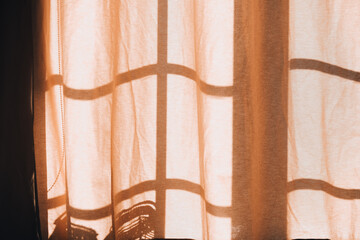 Soft sunlight casts intricate shadows through sheer curtains in a cozy room