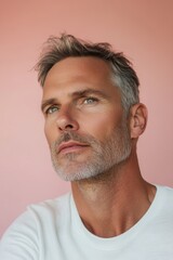 Fototapeta premium Confident mature man showcasing skincare on a soft pastel backdrop
