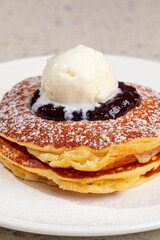 Portion of appetizing sweet pancakes with blueberries and ice cream
